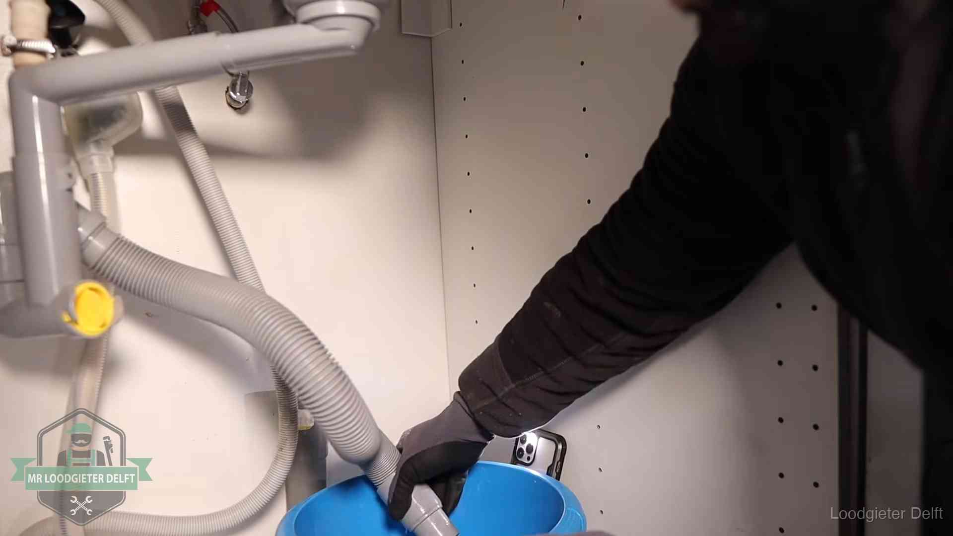 Afvoerslang loopt leeg in een emmer onder de gootsteen in Delft, een klus die je zelf kunt doen