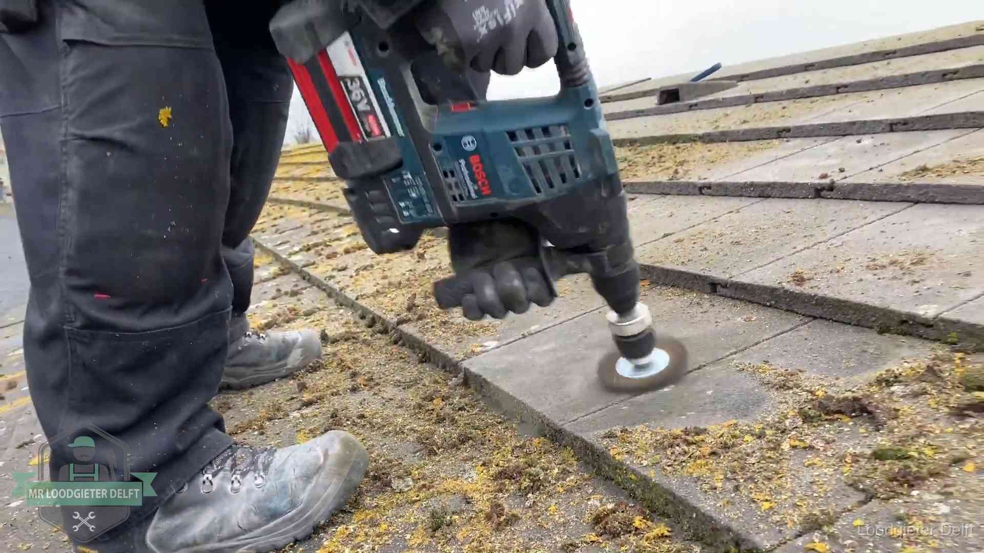 Betonnen dakpannen worden machinaal gereinigd tijdens dakonderhoud in Delft