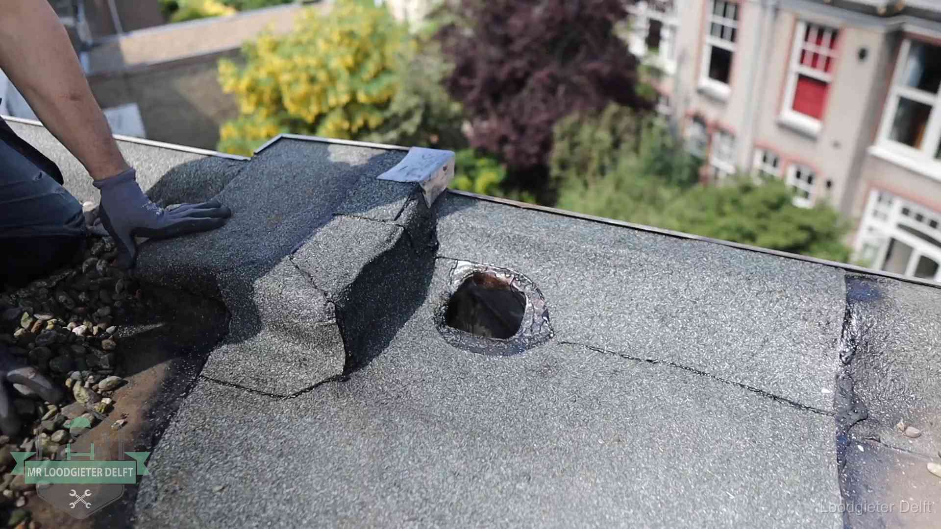 Loodgieter inspecteert een beschadigd bitumen plat dak tijdens een daklekkage-inspectie in Delft