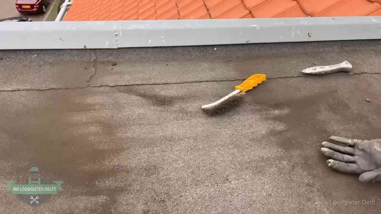 Dakdekker bereidt een bitumen plat dak voor op reparatie bij de daktrim in Delft