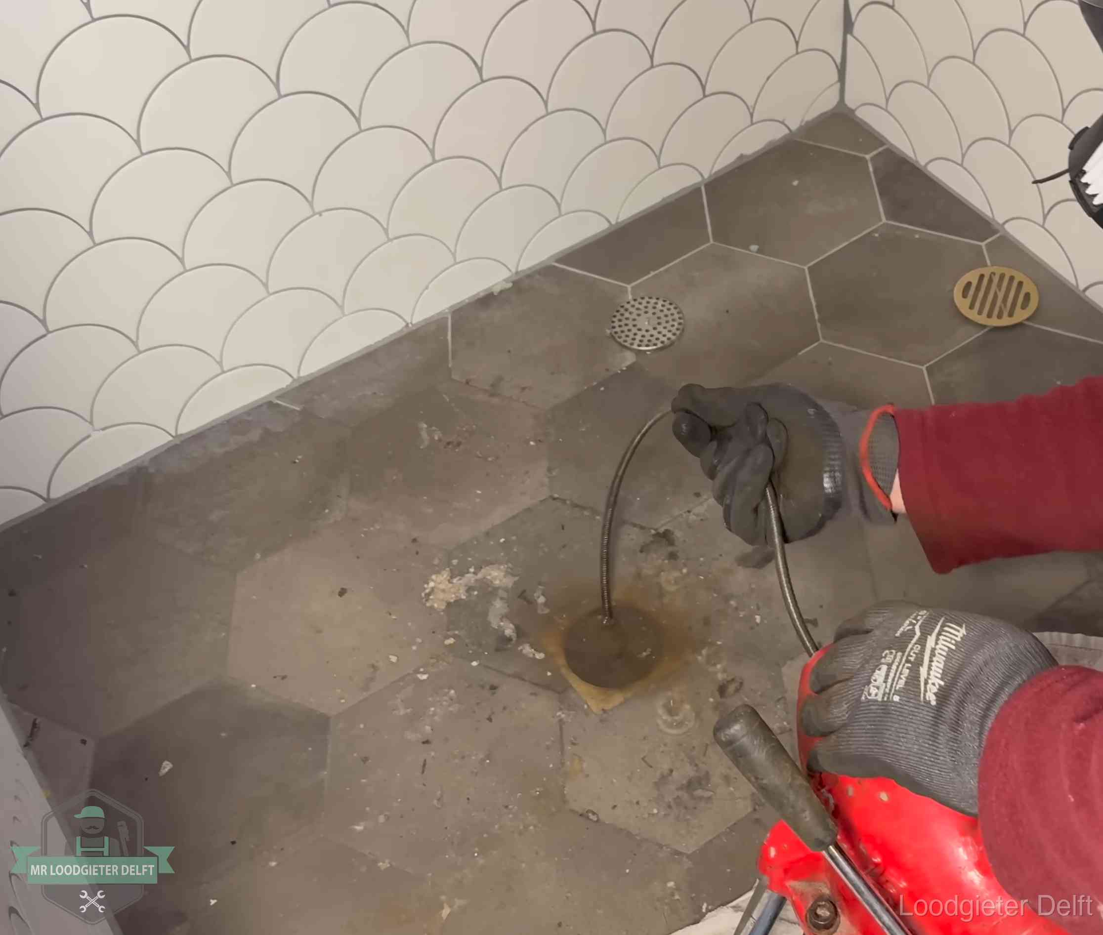 Ontstoppingsveer gaat in een geopend doucheputje in Delft waar het water omhoogkwam