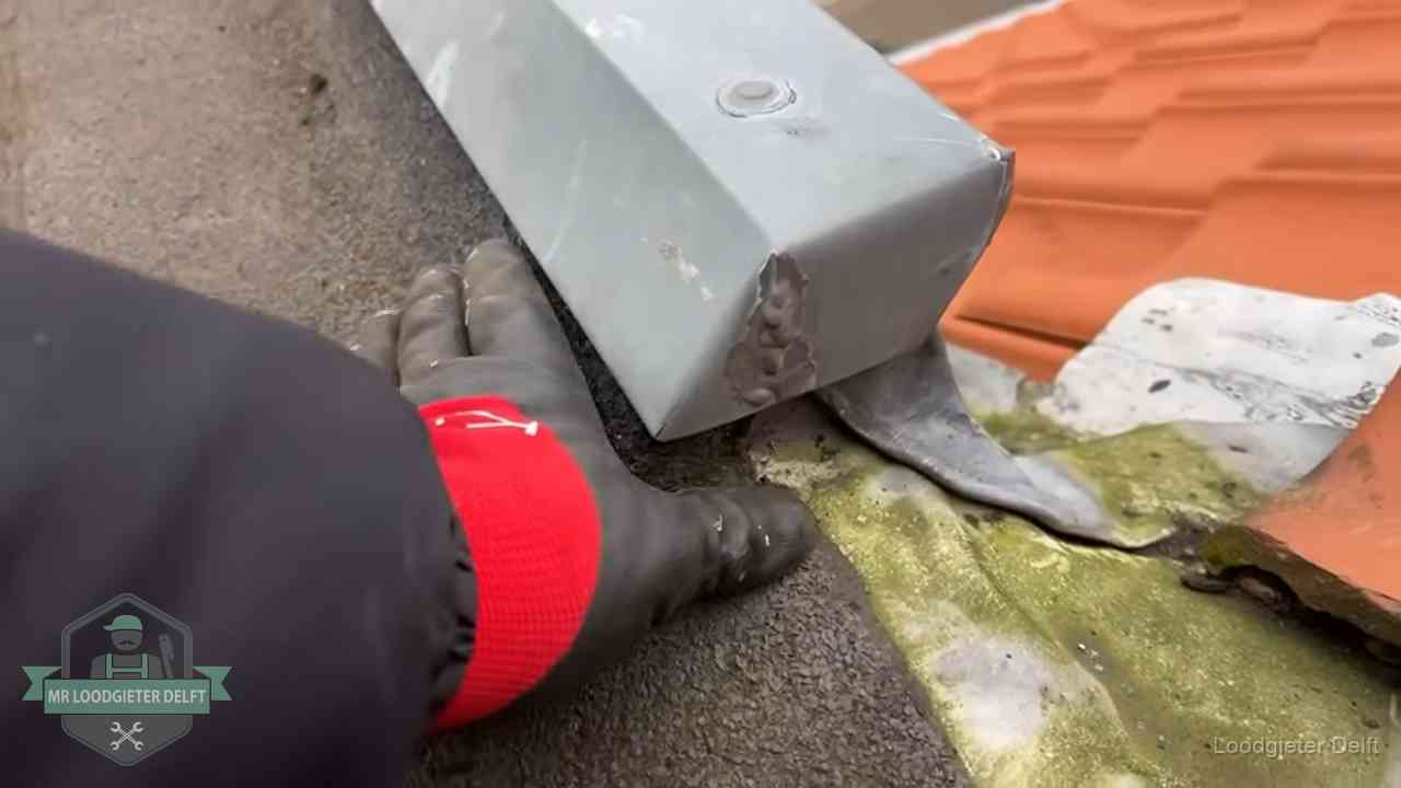 Controle van een zinken hemelwaterafvoer met loodslab bij dakpannen in Delft