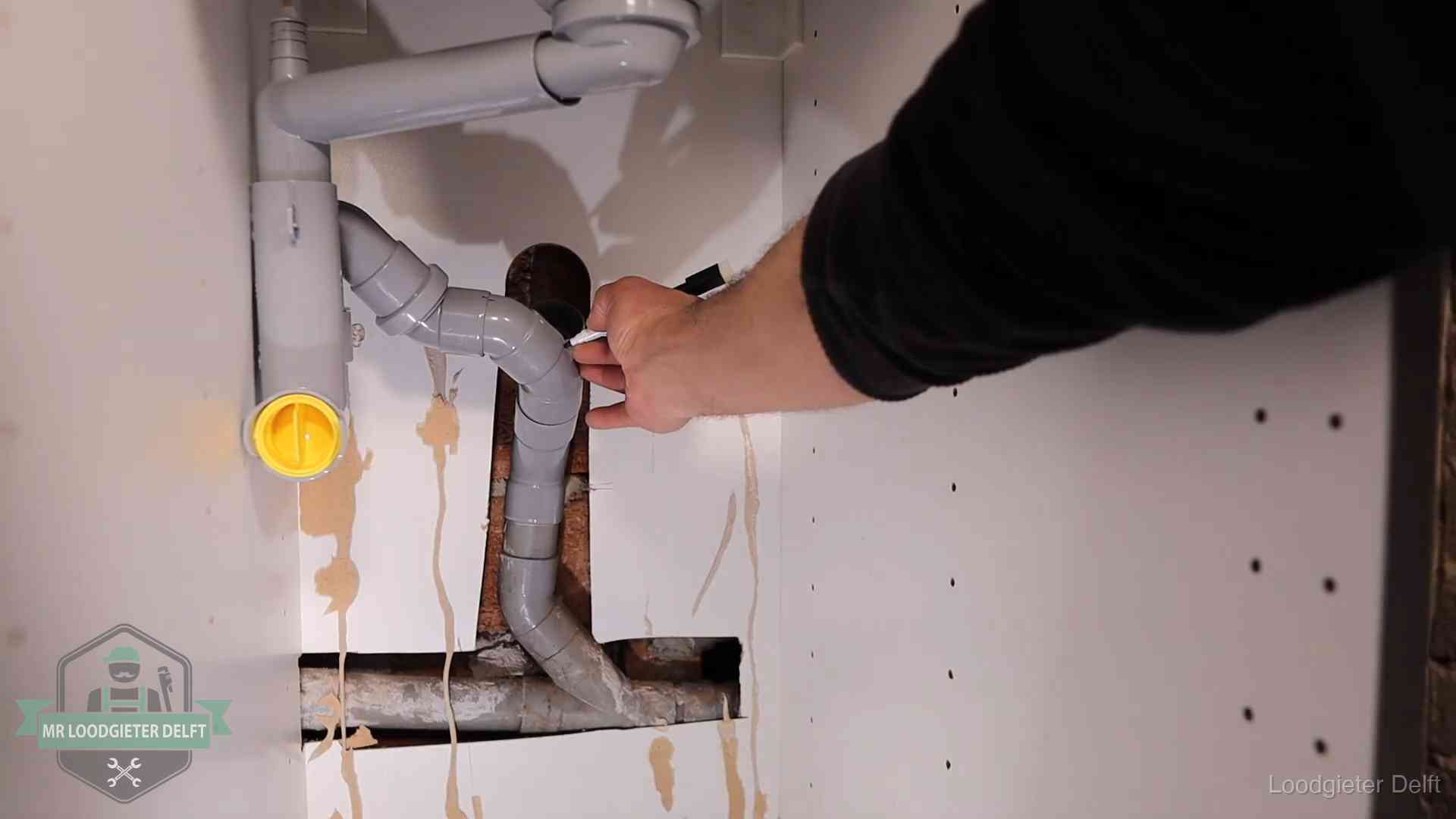 Loodgieter voor verhuurders en bedrijven in Delft Loodgieter markeert een pvc-afvoerbuis onder een gootsteen in Delft