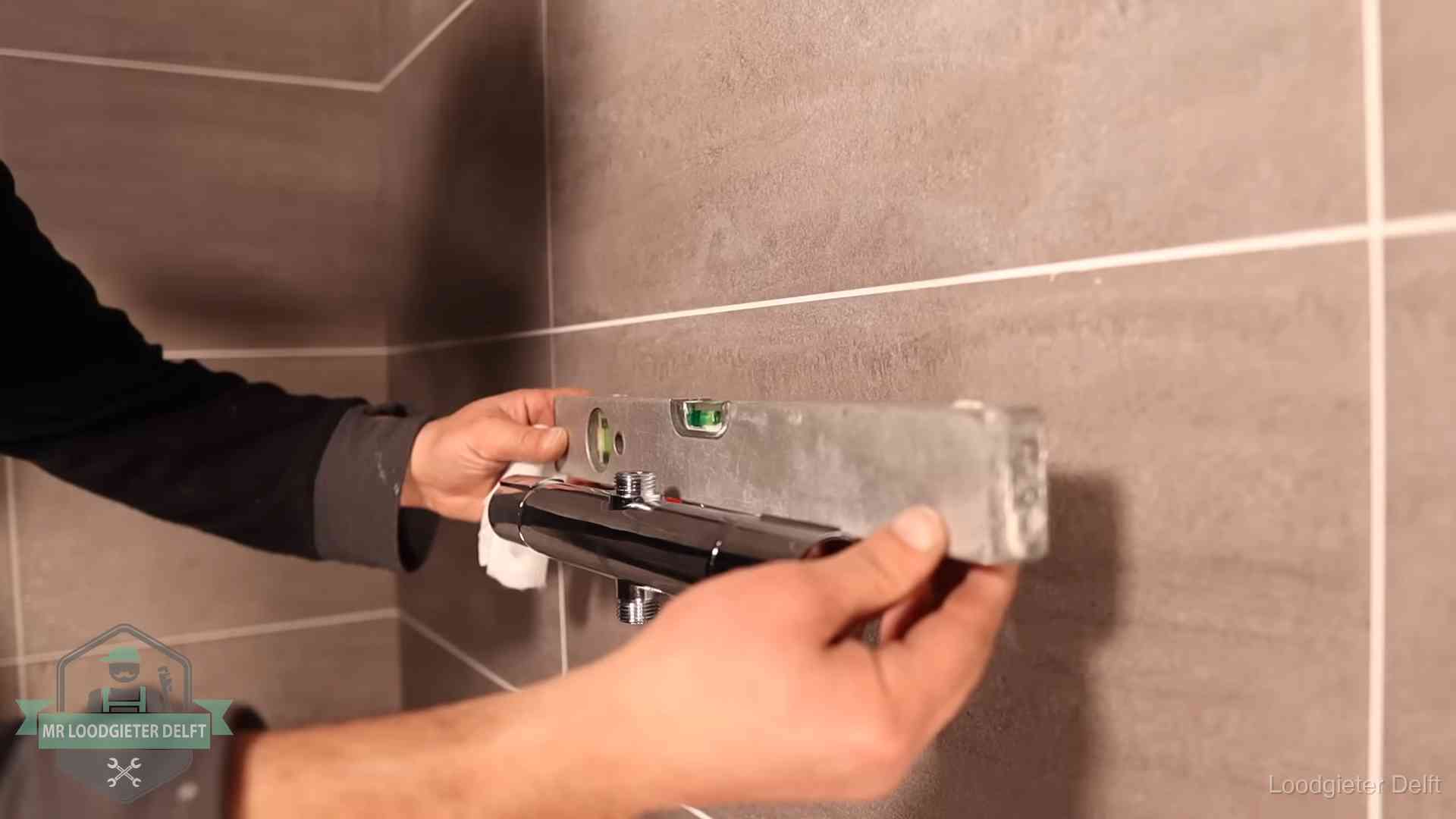 Loodgietersbedrijf voor sanitair in Delft Loodgieter lijnt een douchekraan uit met een waterpas in een woning in Delft