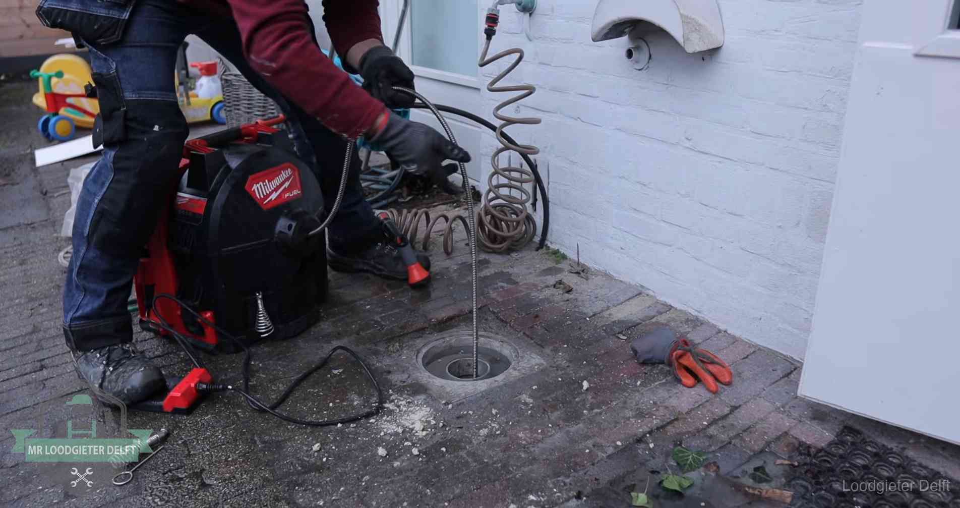 Ontstoppingsputje in de bestrating naast de gevel van een woning in Delft