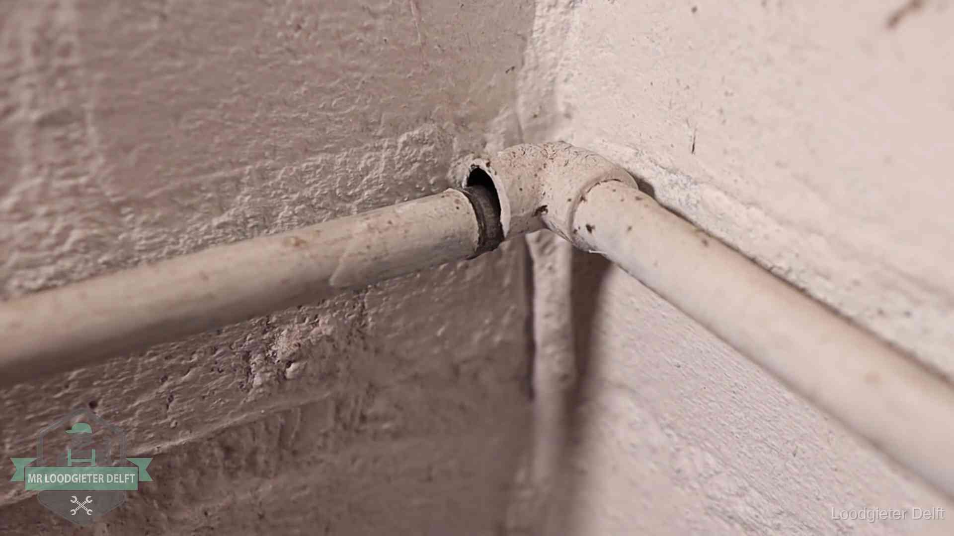 Oude waterleidingen en verborgen lekkage in Delft Oude geverfde waterleiding met een losliggende fitting in een woning in Delft