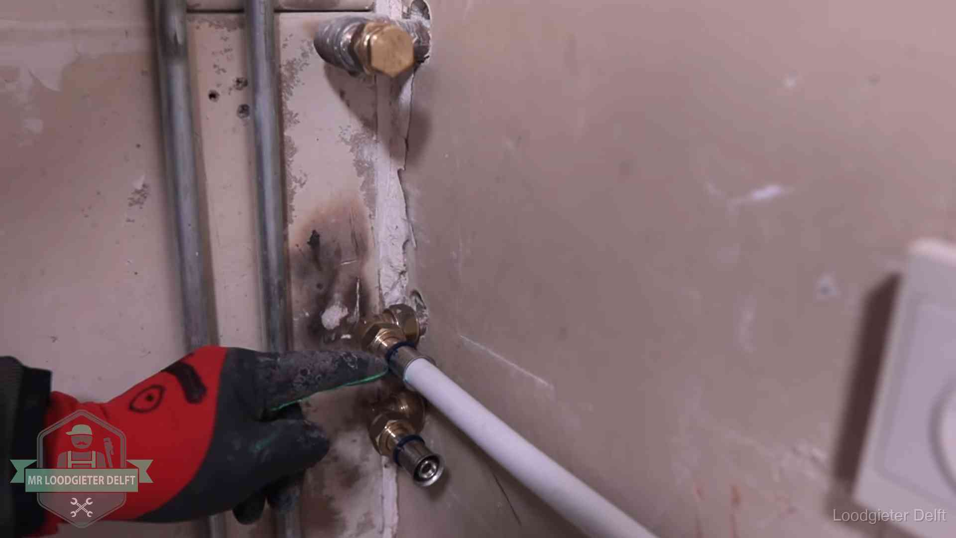 Garantie op loodgieterswerk in Delft Loodgieter wijst de persfitting op nieuwe muuraansluitingen aan in een woning in Delft