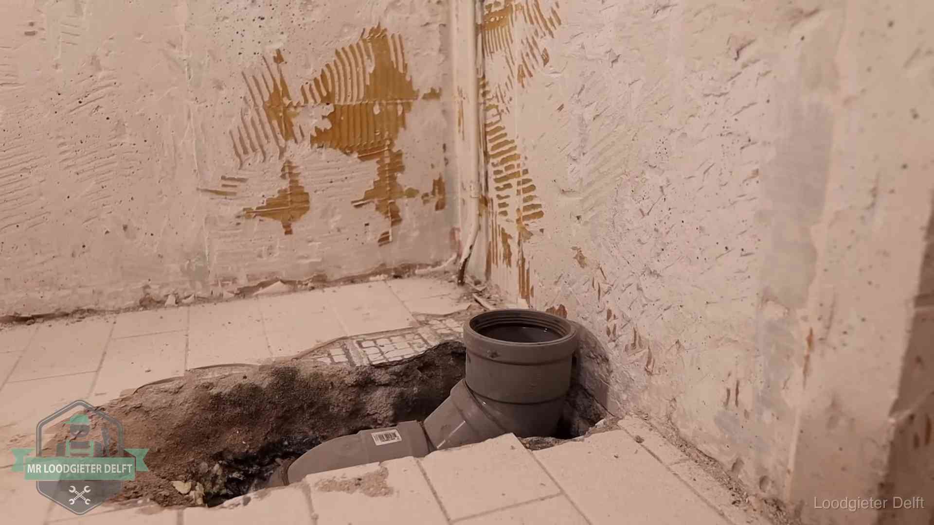Opengebroken vloer met een nieuwe pvc-rioolbocht in een gegraven sleuf in Delft