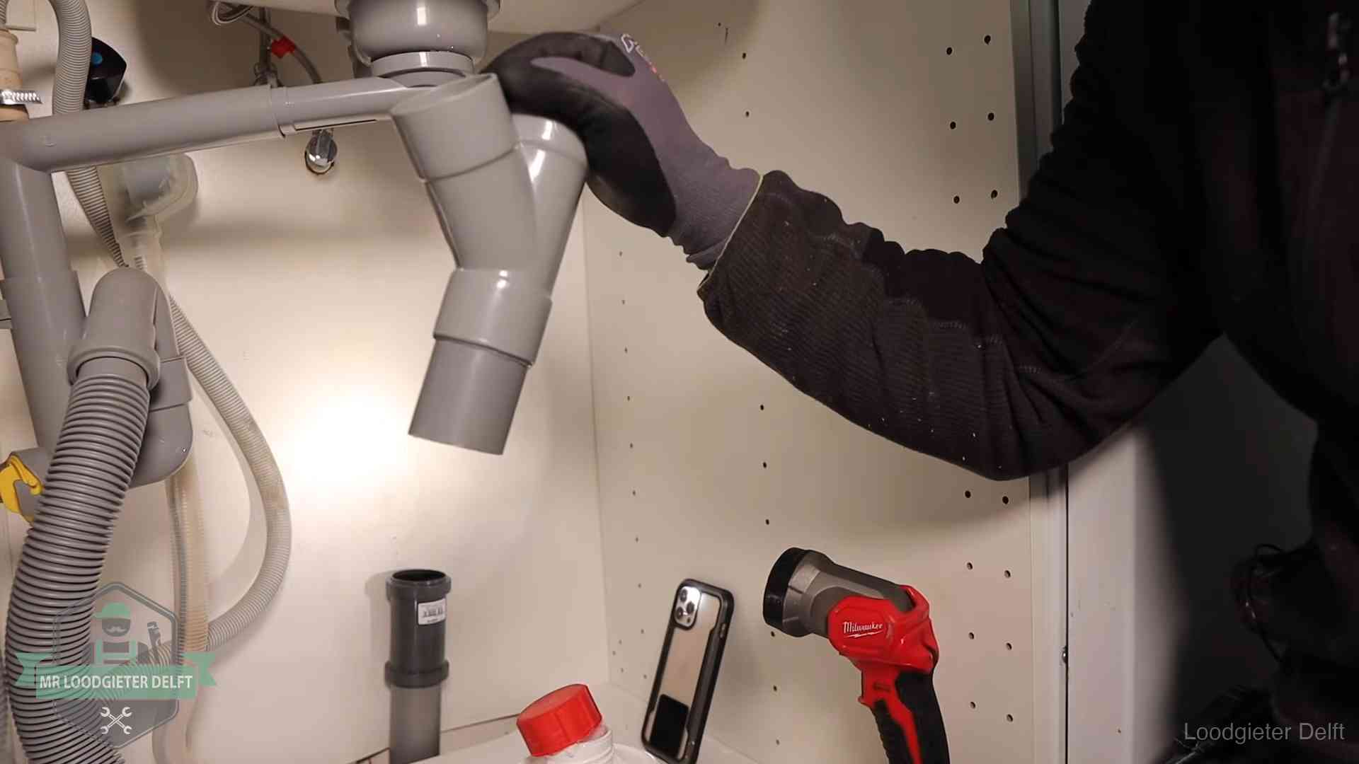 Loodgieter demonteert het sifon- en afvoerwerk onder een gootsteen in Delft bij stankklachten