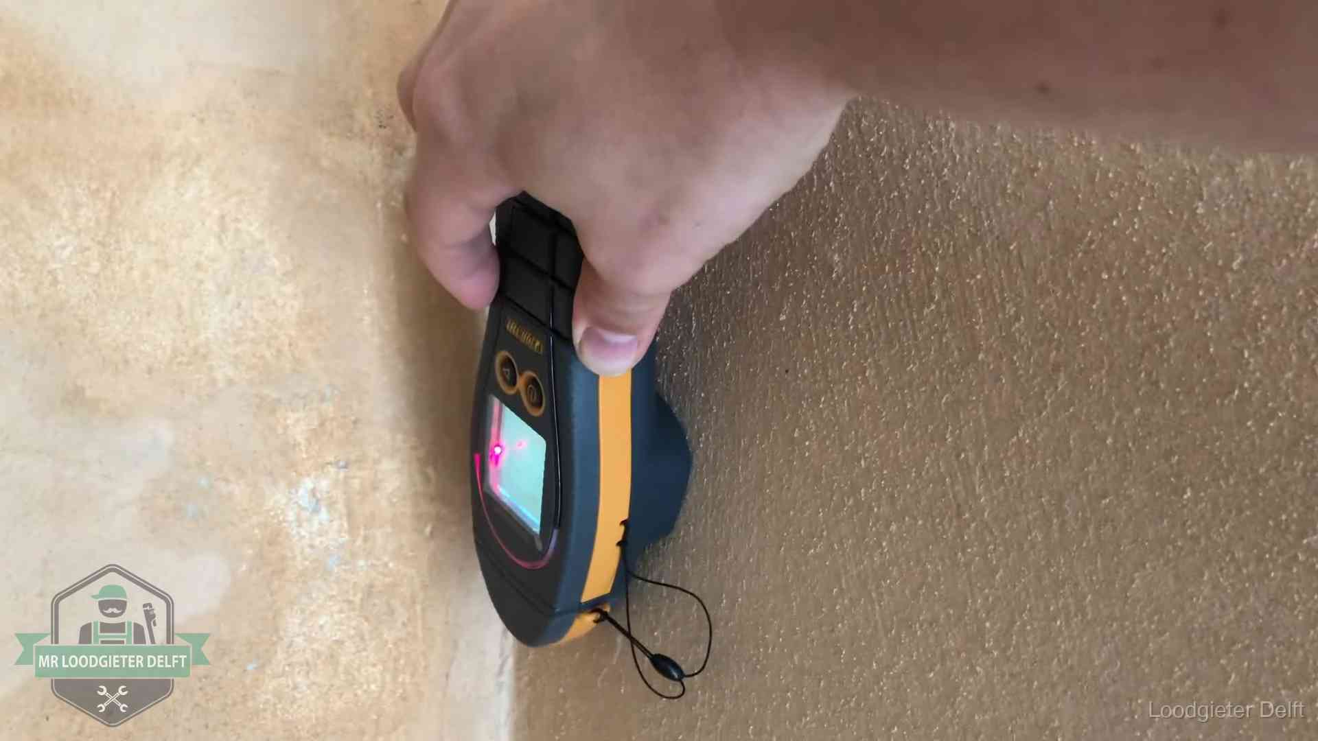 Vochtmeter tegen een muur met vochtplekken tijdens het opsporen van een daklekkage in Delft